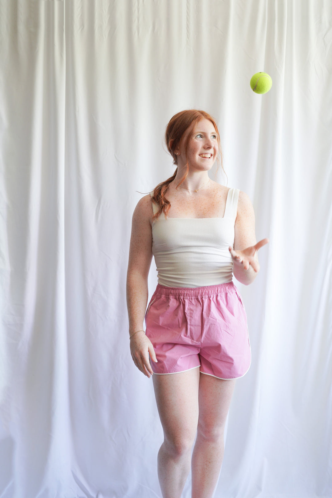 Girl wearing pink tennis shorts with white basic top.  