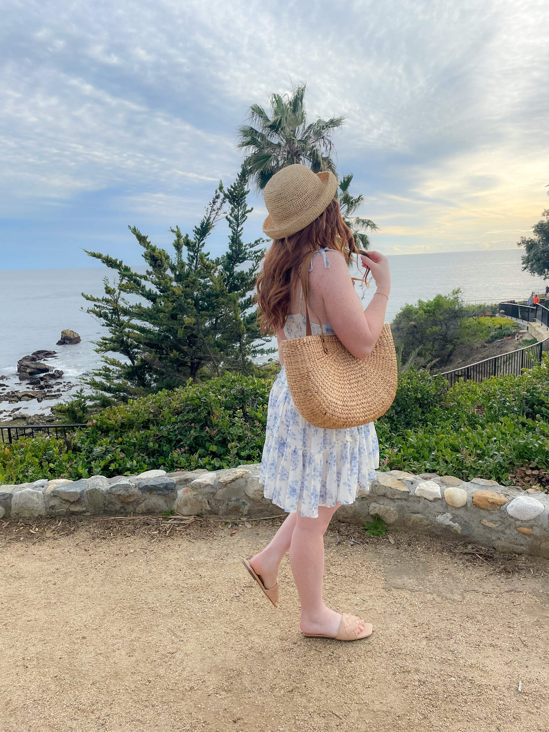 Girl at the beach carrying a grass purse with a leather strap
