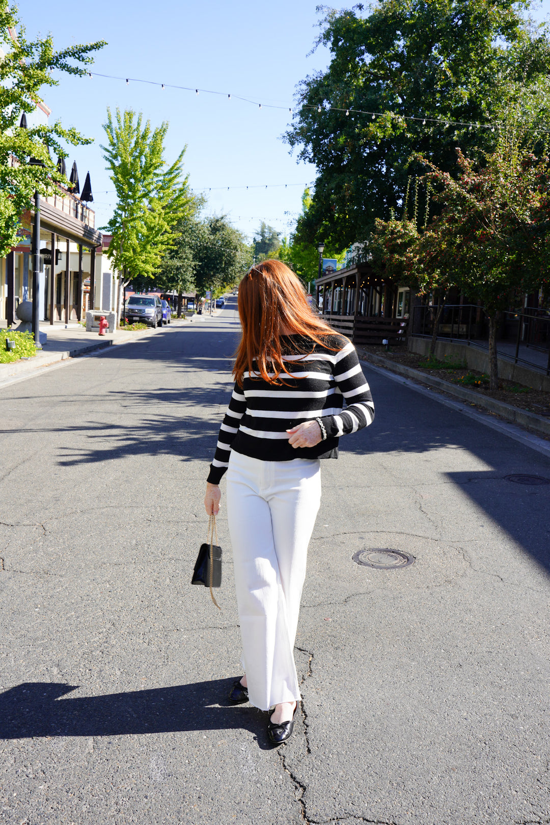 Women wearing black and white stripped sweater and white wide leg jeans