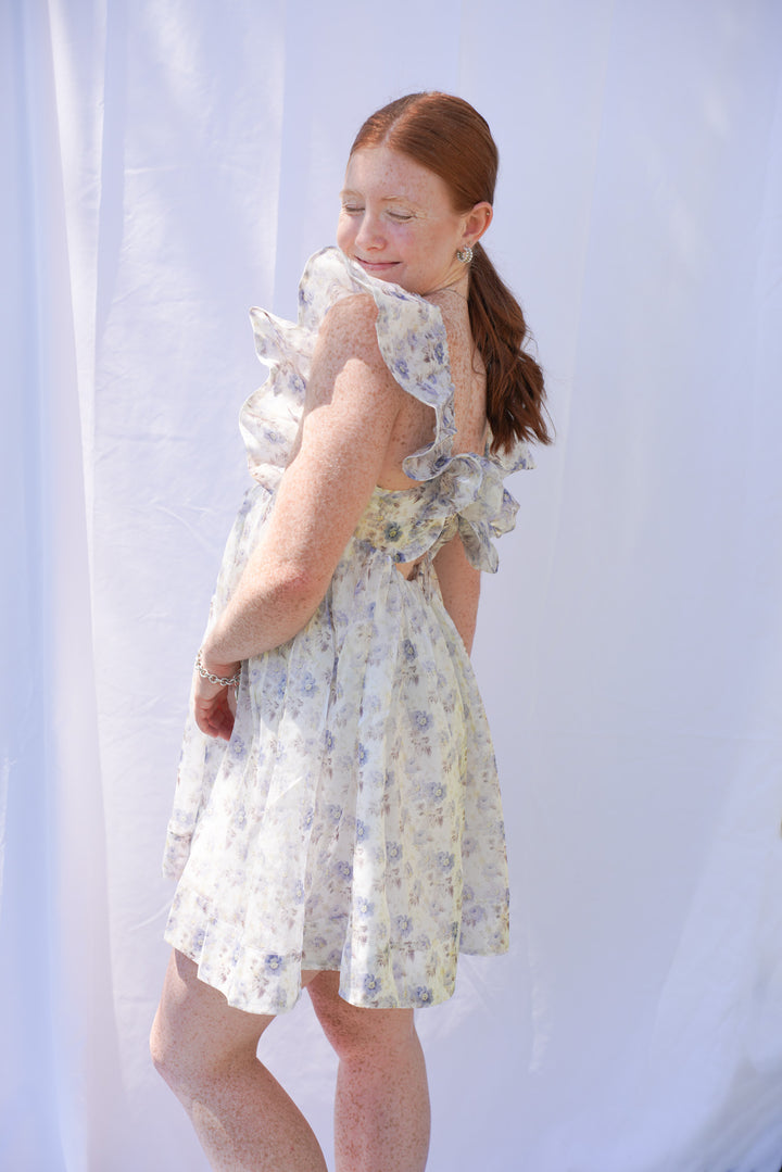 Women wearing blue floral organza dress with ruffle sleeves and bow back