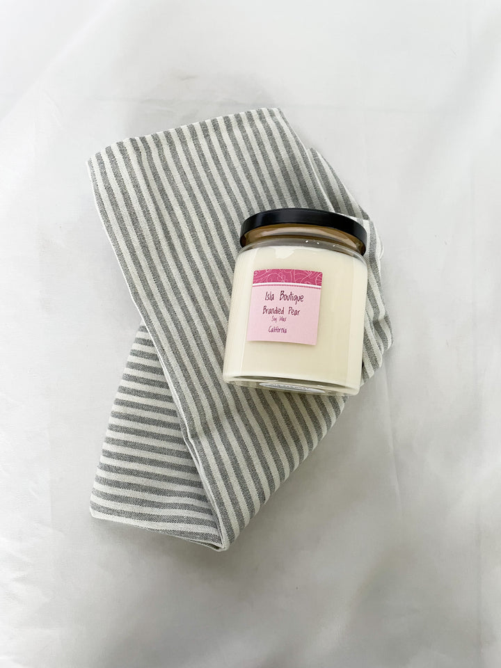 brandied pear scented soy candle with grey and white stripped tea towel