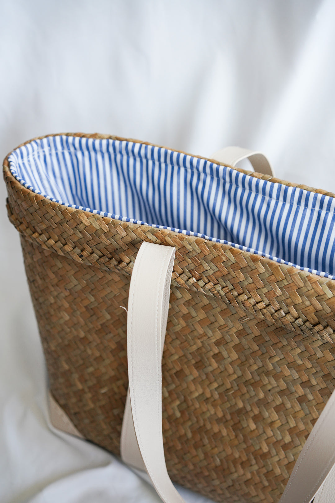 Drawstring Sedge Seagrass Basket tote bag with blue and white inner lining and faux leather handles