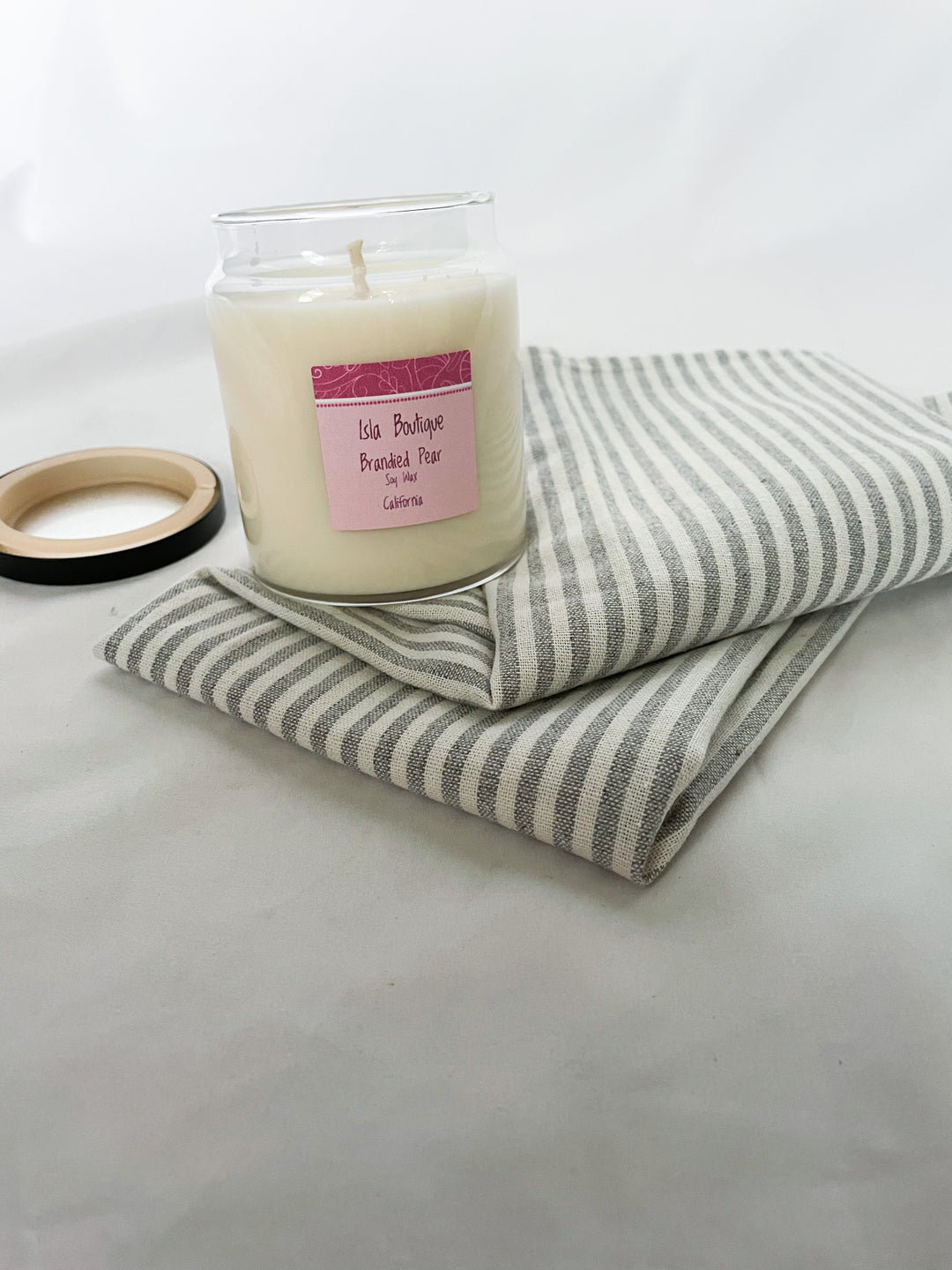 brandied pear scented soy candle with grey and white stripped tea towel