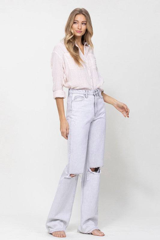 90’s style vintage flare jeans that are light-wash denim and have distressed knees.