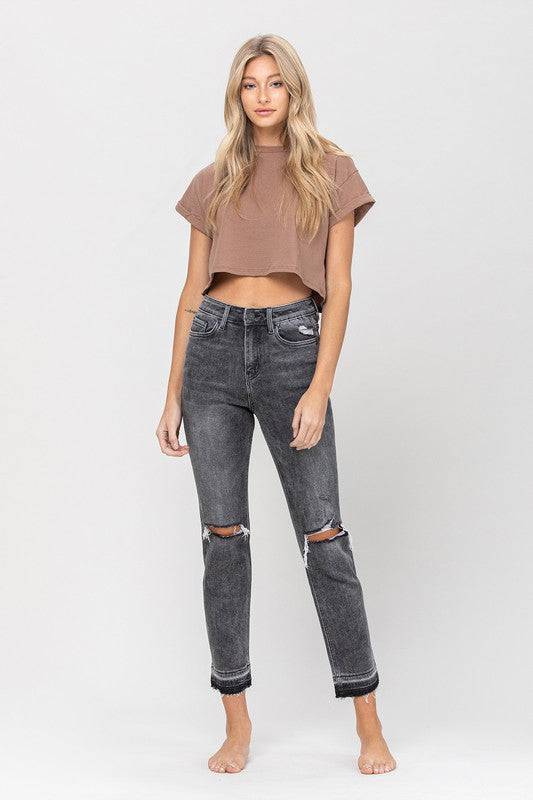 Black wash denim jeans. The leg of the jeans are a straight leg style. They fit nice and loose but don’t flare. They have distressed knees on both sides. Around the ankle the black is darker and the bottom is frayed. It has distressed pockets and a medium rise waist.
