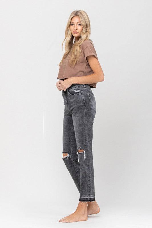 Black wash denim jeans. The leg of the jeans are a straight leg style. They fit nice and loose but don’t flare. They have distressed knees on both sides. Around the ankle the black is darker and the bottom is frayed. It has distressed pockets and a medium rise waist.