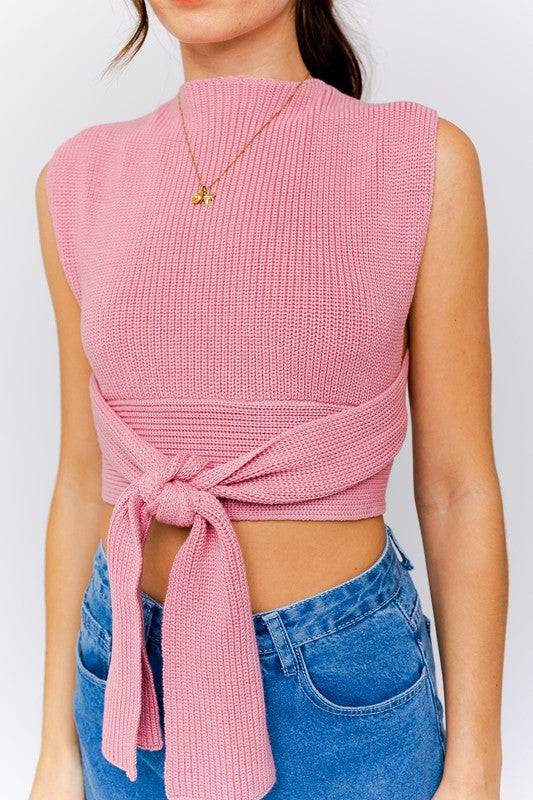 A halter knit crop top. The top is a rose pink. The neck is a halter that wraps around the neck. The material is a woven knit material. And the waist of the top ties around the back or the front