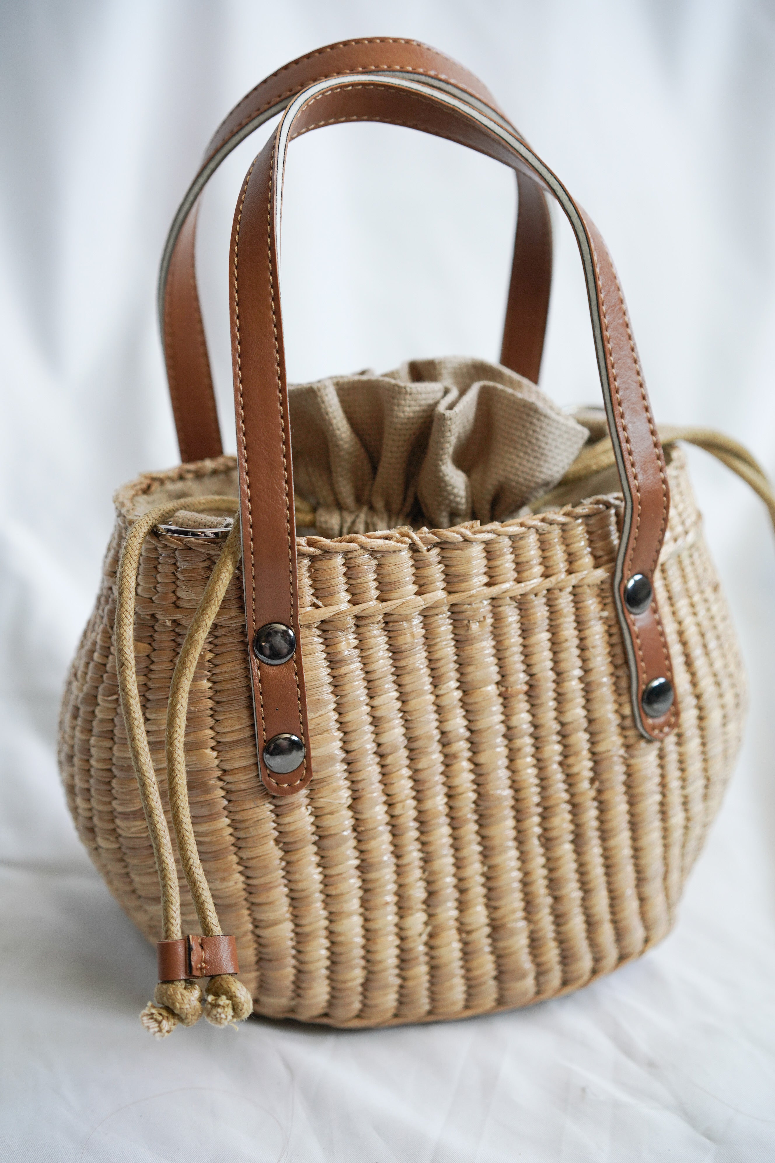 Handbag collection made from pliable sedge seagrass with faux leather handles and a convenient drawstring closure
